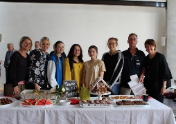 Gropup of mostly female mentors and students standing behind a table of food